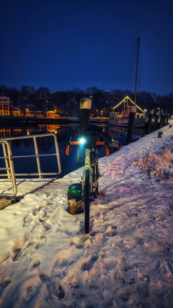 Fahrrad am Hafen in Flensburg bei leichter Dunkelheit auf schneebedecktem Untergrund